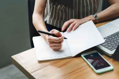 woman holding pen beside laptop